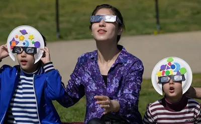 Personas mirando un eclipse solar con gafas de eclipse certificadas puestas